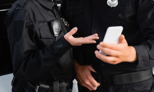 Oficiales de policía discutiendo imágenes grabadas en un teléfono celular.