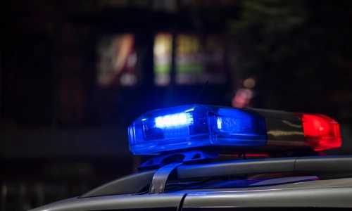 Las luces rojas y azules de un coche de policía parpadeando en su techo por la noche.