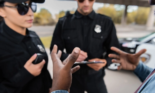 Un conductor hablando con dos oficiales de policía sobre los detalles de un accidente.