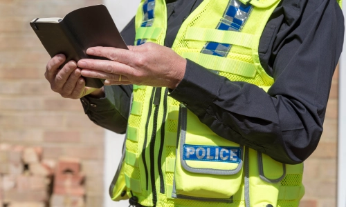 Un oficial de policía sosteniendo un cuaderno y revisando los detalles recopilados para un informe.