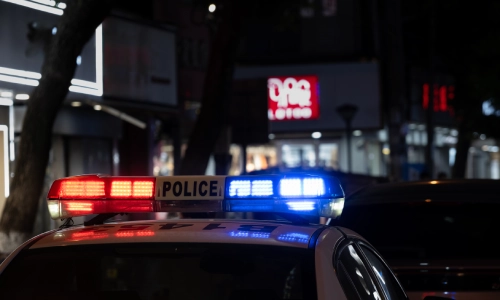 Un coche de policía con sus luces rojas y azules parpadeando en la ciudad por la noche.