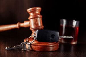 Car keys, a gavel, and an alcoholic beverage signifying consequences for a drunk driver.