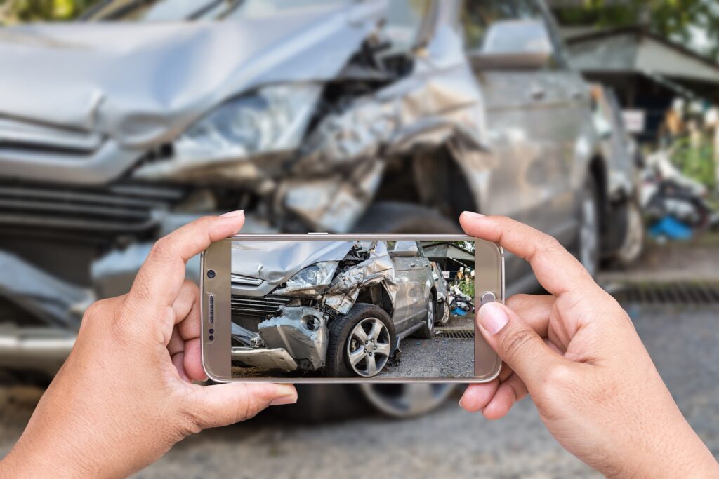 A close up of a woman holding a phone taking pictures after a car accident. 