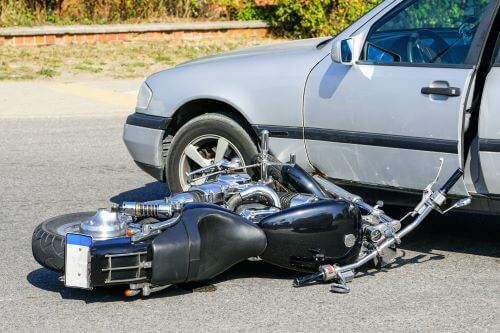 A motorcycle is seen lying on its side after colliding with a car