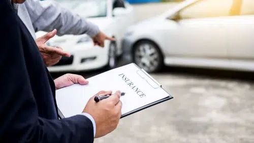 An insurance adjuster goes over auto insurance policy details with a driver.