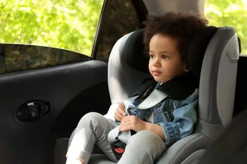 A child is pictured sitting in a car seat.