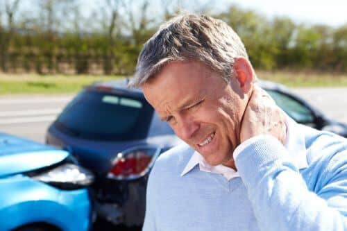 A man rubs his neck after suffering a bodily injury in a car accident