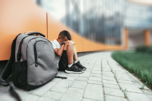 A neglected child is is left outside at school.