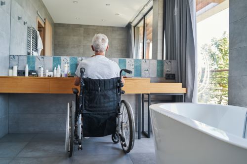 A man with a spinal cord injury sits in his wheelchair at the bathroom counter.