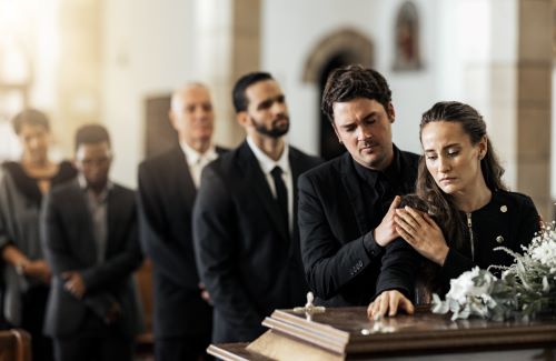 A family stands at the casket of a deceased family member at a funeral.
