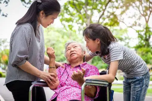 An elderly woman with dementia is cared for by her daughter and granddaughter.