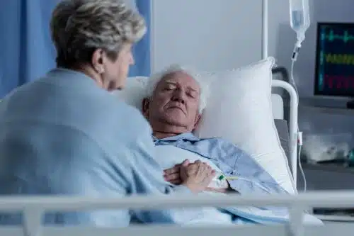 An older male patient is alseep in his hospital bed after a TBI.