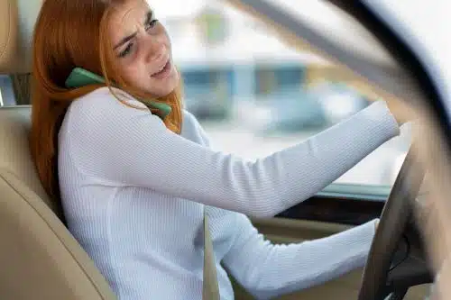 A distracted woman talks on the phone while driving her car before an accident.