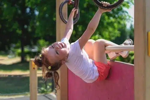A little girl hangs upside down from a jungle gym at daycare in Georgia.