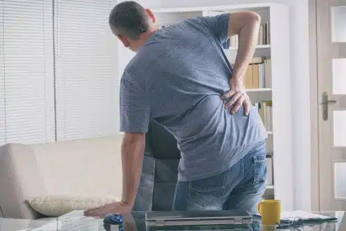 An injured man holds his back with a spinal injury.