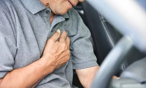 A man in a car holding his chest after being injured in a car accident.