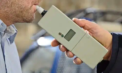 A police officer giving an impaired driver a breathalyzer test.