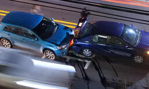 A long exposure overhead shot of a car accident between two vehicles while traffic drives by.