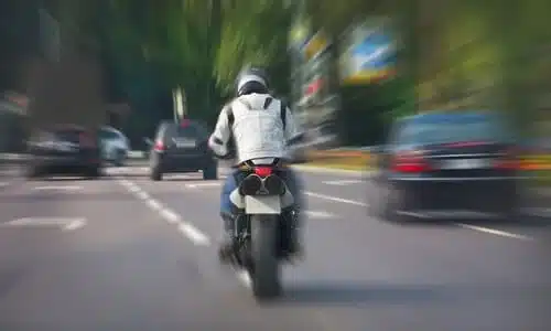 A motorcycle speeding along a city street next to other vehicles.