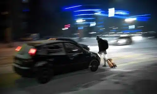 A motion-blurred shot of an SUV about to collide with a pedestrian at night.