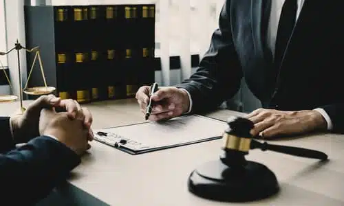 A lawyer taking notes on a clipboard while discussing a case with a client.