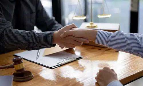A personal injury lawyer shaking hands with a client after an agreement has been reached to work together.