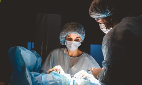 A team of doctors performing invasive surgery on a patient in an operating theater.