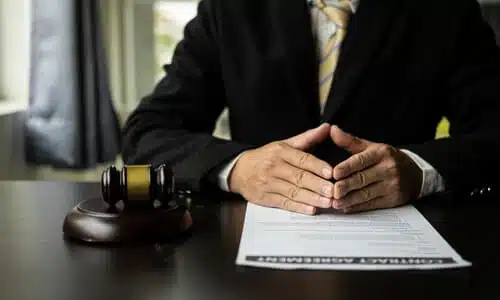 A chest shot of a personal injury lawyer with his hands steepled at a desk next to a gavel and a soundblock.