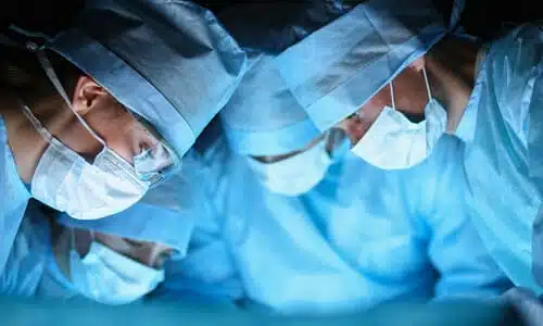 Surgeons performing a medical procedure in an operating room on a patient.