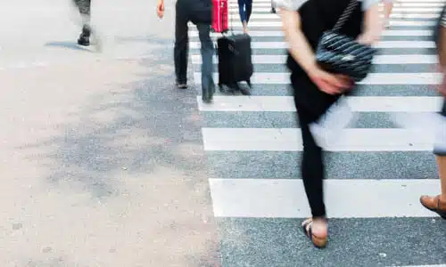 A motion-blurred image of pedestrians at a crosswalk making their way across a street.