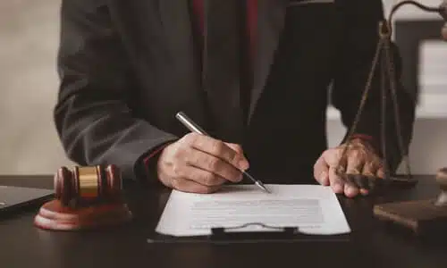 A personal injury lawyer reviewing details of an insurance policy at a desk using a pen.