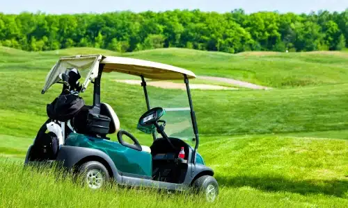 A golf cart parked on the fairway of a course in the daytime.