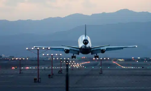 An airplane in the early evening taking off after taxiing on a runway.