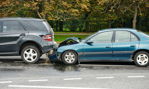 A rear-end accident between two cars on a gloomy afternoon.