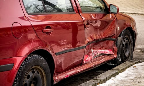 A red hatchback with a damaged right side after a side impact accident.