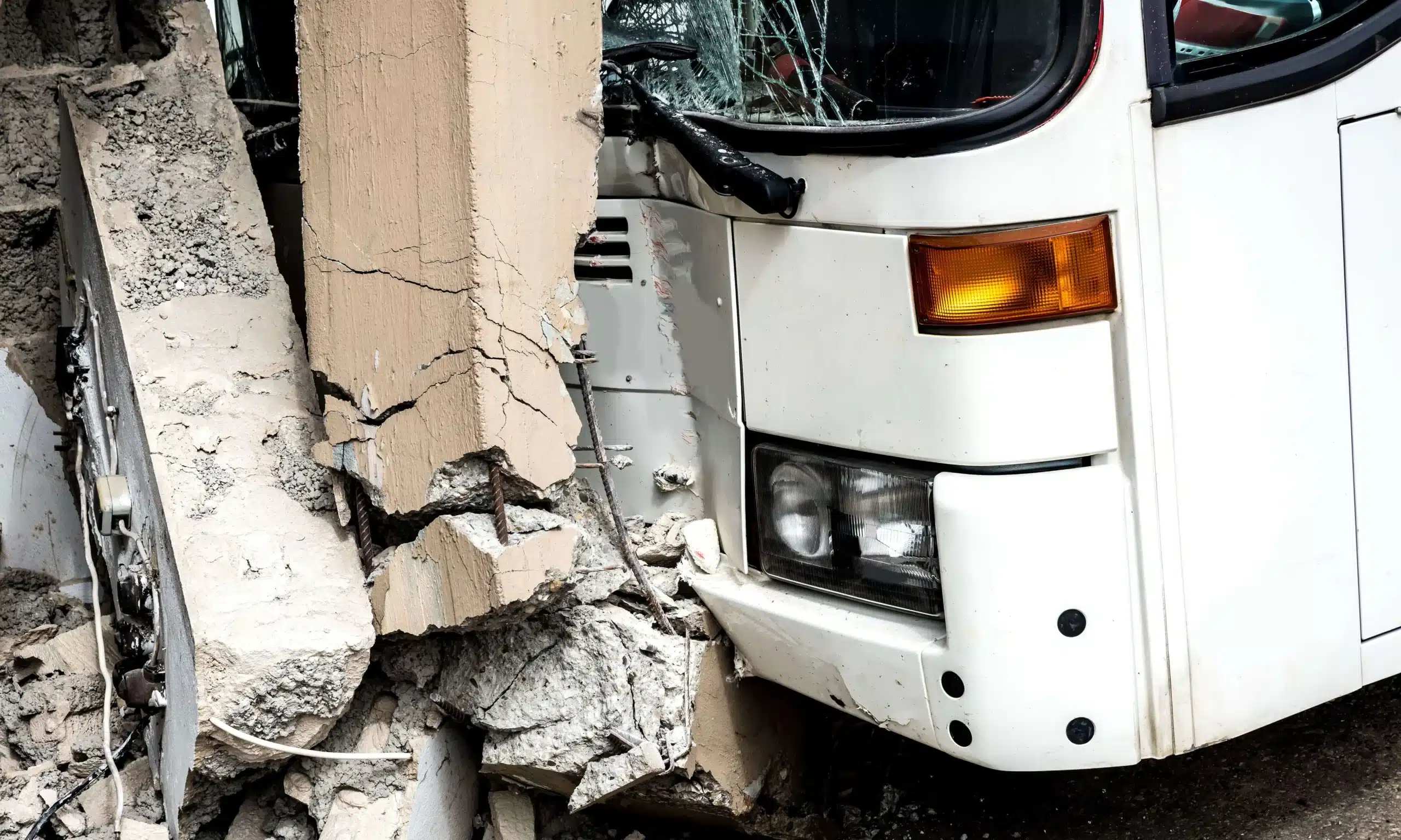 A closeup of a bus accident where the bus crashed into a concrete pillar.