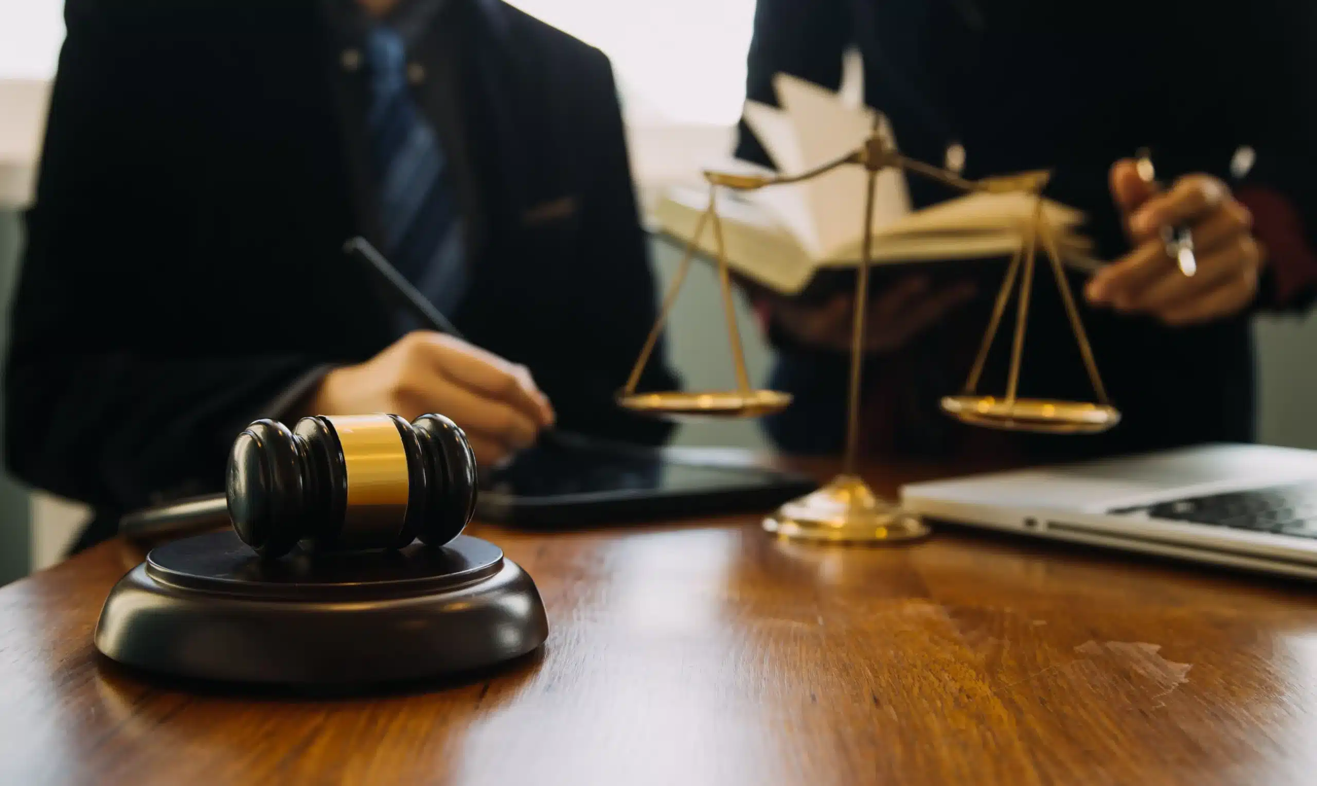 Two lawyers working on a client's case with open law books and pens in hand.