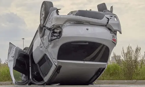 An upside-down hatchback on a highway after a dangerous accident flipped it over.