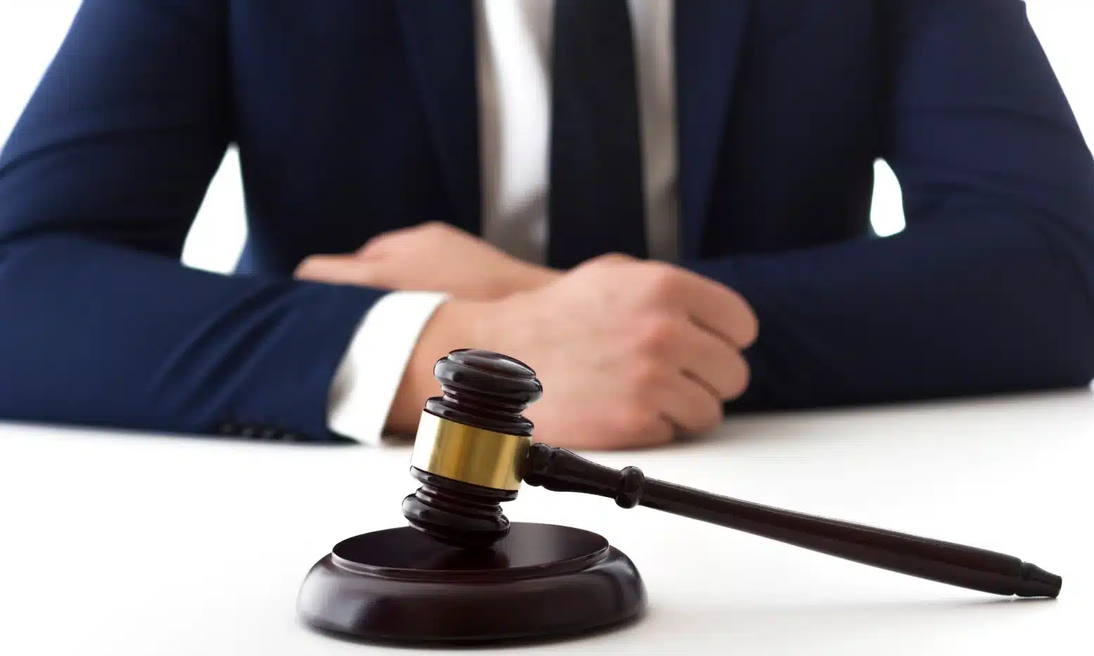 A personal injury lawyer at a white desk seated behind a gavel and soundblock.