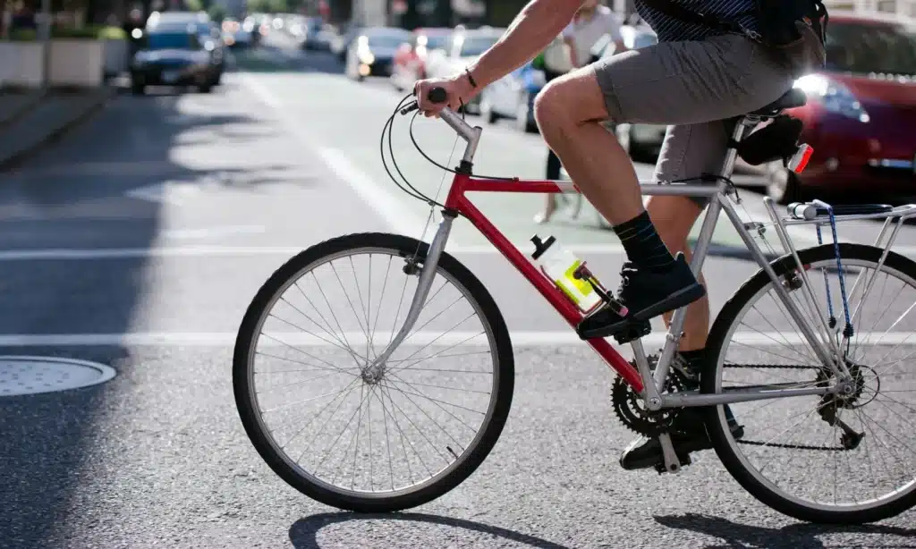 A cyclist crossing the road on his bike in the middle of the day.