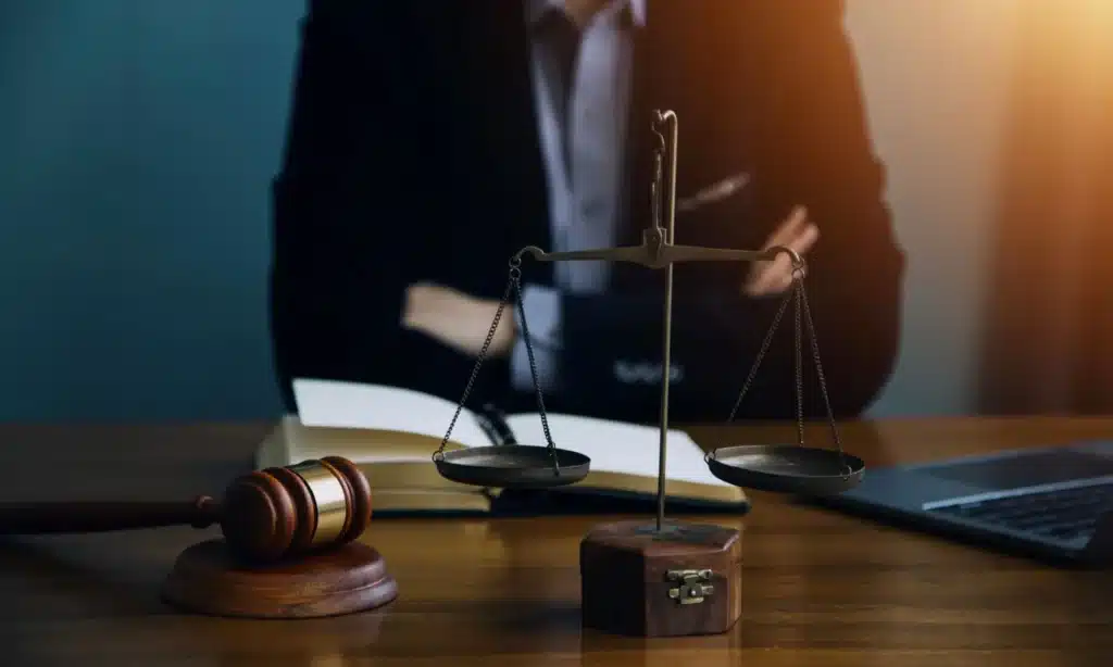 A lawyer in an office sitting confidently with crossed arms at a desk.