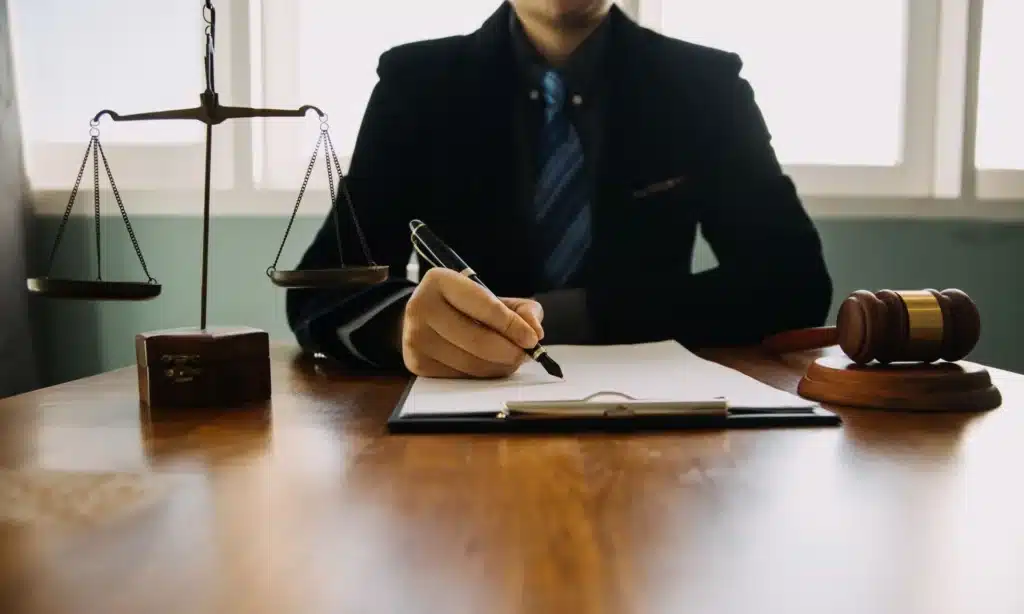 A lawyer seated at a wooden desk and working on documents for an insurance claim.