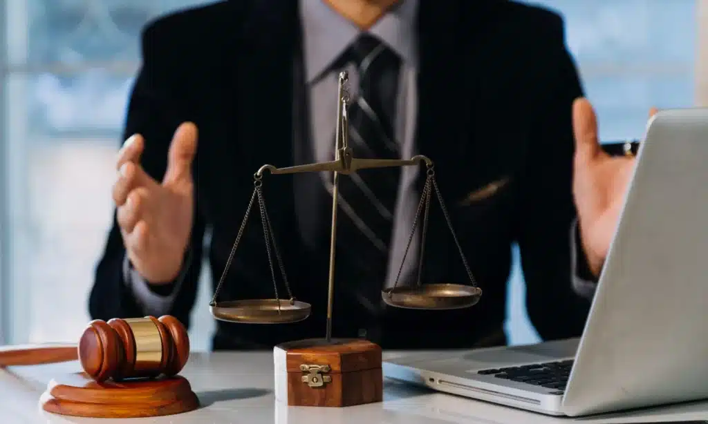 A lawyer at his desk expressing ideas with his hands while explaining details of a case to a client.