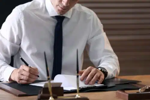 An attorney at a desk with a clipboard in front of him holding papers related to his client's case.