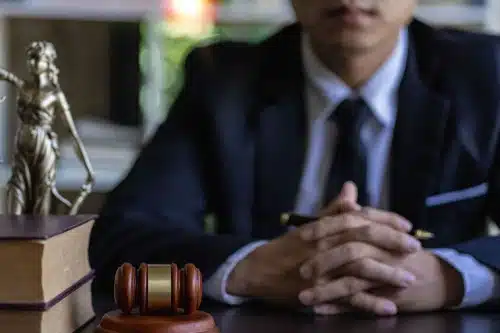A personal injury lawyer in his office clasping a pen in between his hands as he waits for a client.