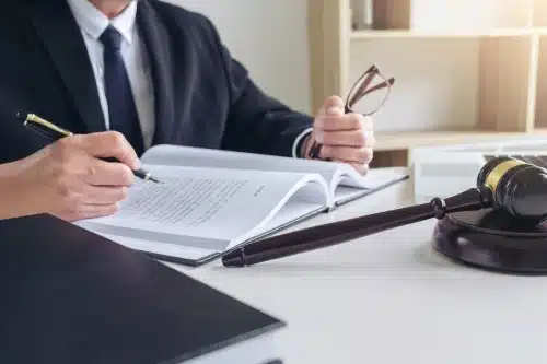 A personal injury attorney with an open law book spread in front of him as he works on a client's case.