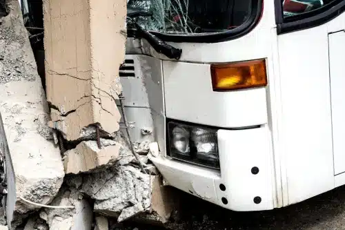 A closeup of a bus accident where the bus crashed into a concrete pillar.