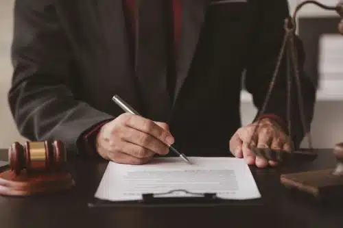 An attorney seated at a desk and highlighting important lines on a client's insurance policy with a pen.