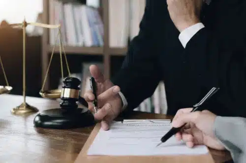 A lawyer twirling a pen in his hand while listening to a client discuss their situation.