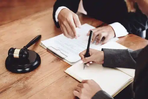 A lawyer taking notes in a laptop while a client explains why they need to make a claim.